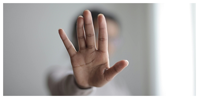 Eine Frau streckt zur Abwehr die Hand aus.