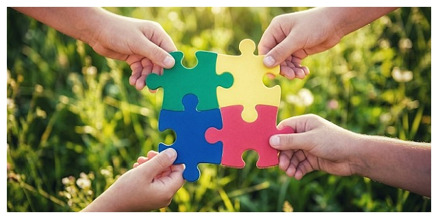 Vier farbige Puzzleteile greifen ineinander