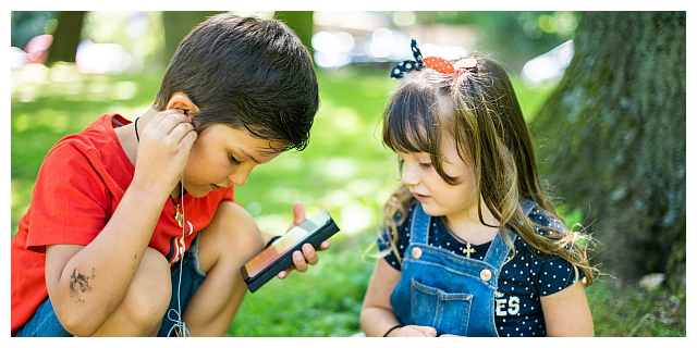 Zwei Kinder sitzen an einem Smartphone